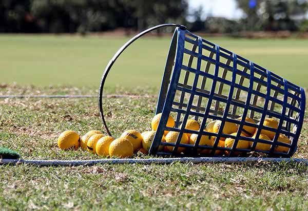 A wire basket of range balls tipped over on the practice tee.